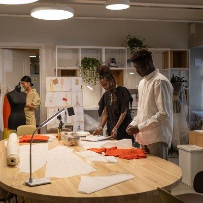 A small fashion design team laying out pattern pieces on a large table in a bright studio