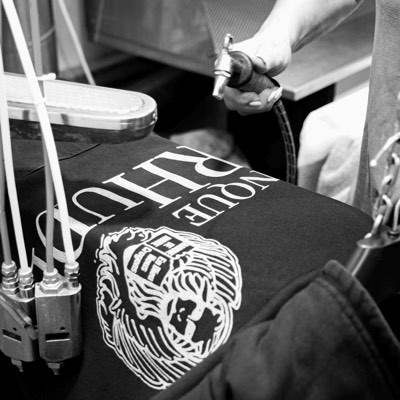 A heavyweight black t-shirt with a white screen print being inspected by hand