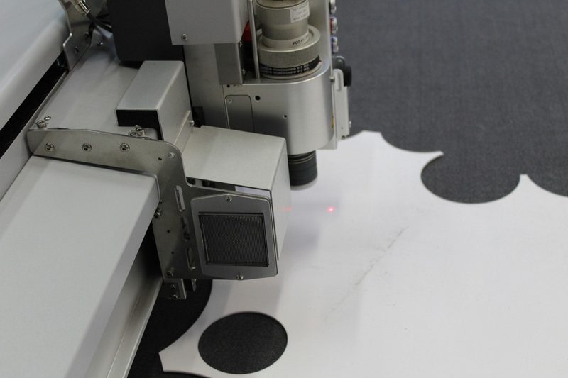 An automated cutter moving over laid fabric in a cutting room