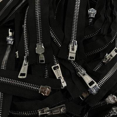 A cluster of metal zipper pulls and tapes on black fabric