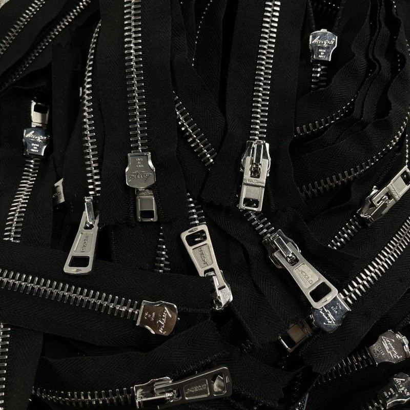 A cluster of metal zipper pulls and tapes on black fabric