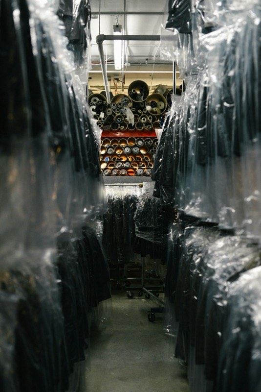 Finished garments hanging in protective plastic covers on a warehouse rail