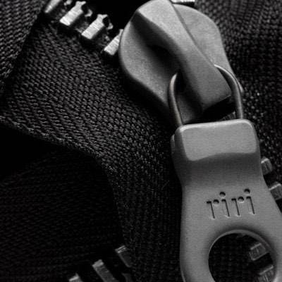 Close-up of a riri zipper pull and metal teeth on black fabric