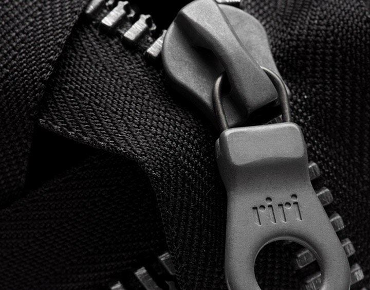 Close-up of a riri zipper pull and metal teeth on black fabric