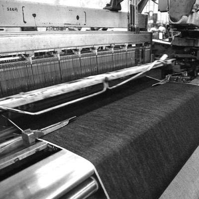 A roll of denim being fed through a fabric spreading machine
