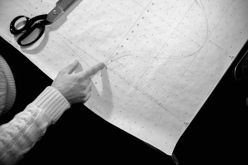 A hand indicating pattern markings on fabric laid ready for cutting