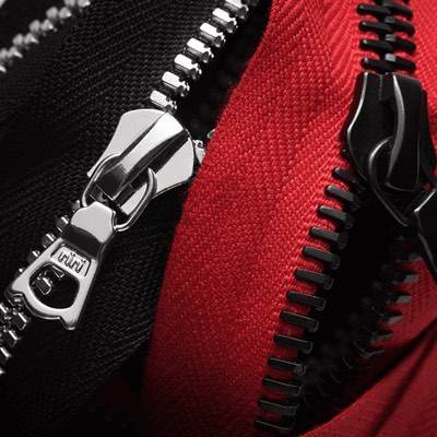 Two metal zippers side by side, one on black fabric and one on red